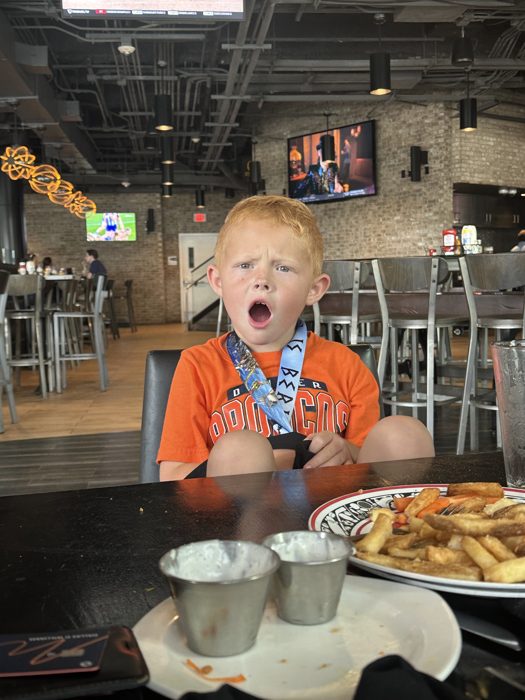 One of the kids lets out a big yawn between bites of fries at a lively sports bar.