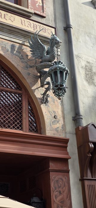 An ornate dragon-shaped lamp bracket hangs above one of Diagon Alley's storefronts.