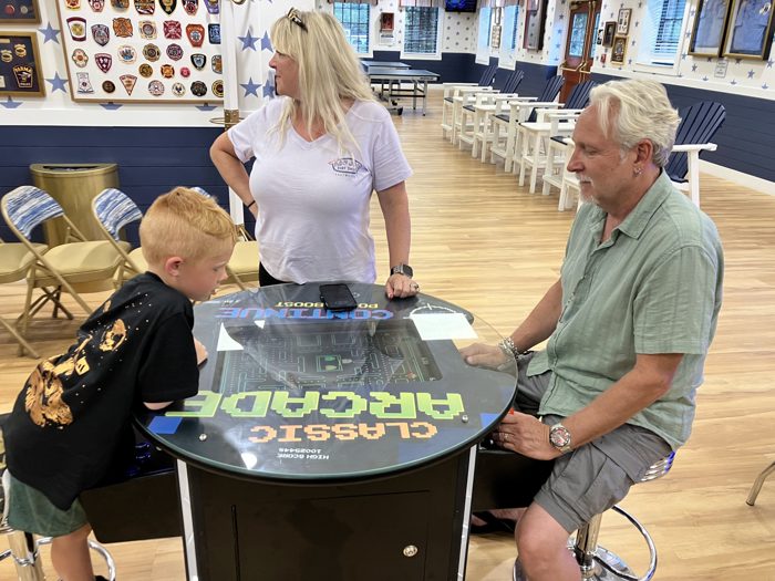 One of the kids leans in for a round of tabletop Pac-Man while the family gathers around in the clubhouse arcade.