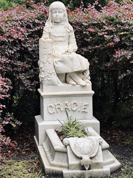 A seated robed figure crowns a weathered family monument at Bonaventure Cemetery.