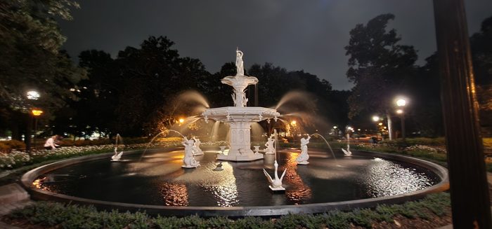 Forsyth Park's grand fountain lit up against the evening sky.