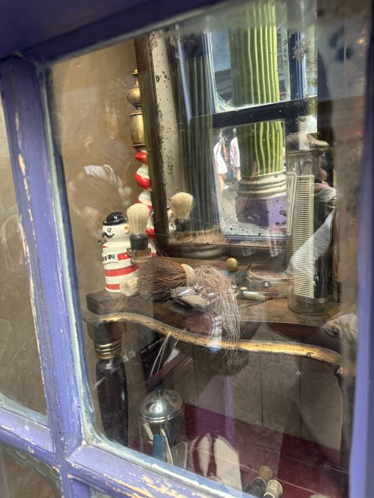 Catching our own reflection in a weathered shop window while snapping photos along the alley.