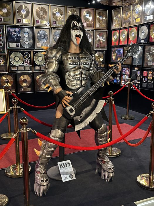 The KISS Demon figure stands guard with his bass amid a wall of gold records.