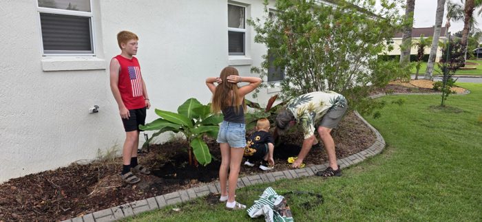 A family friend and the two younger kids dig in together while the oldest looks on.