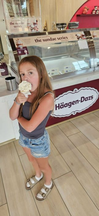 One of the kids takes a big bite out of her ice cream cone at the Häagen-Dazs counter.