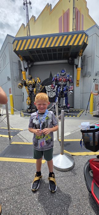 One of the kids grinning in front of Bumblebee and Optimus Prime at the Transformers photo op.