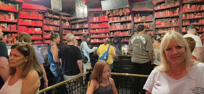 Browsing the eerie red-lit bookshelves at Gideon's Bakehouse while the cookie line winds through the shop.