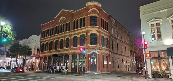 Ornate French Quarter-style facades glowing along the evening street.