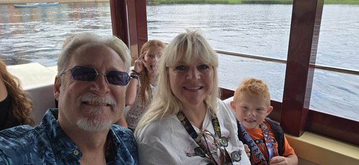 The family leans in for another selfie on the water taxi as the canal drifts by outside the windows.