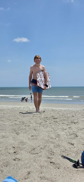 One of the kids heads back up the beach with his board after a round in the waves.
