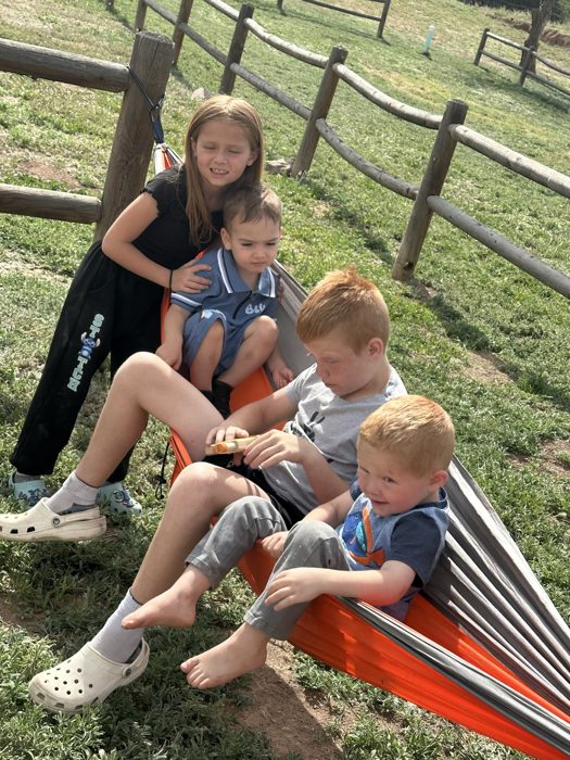 Kids piled together on the orange porch swing for a sunny family moment.