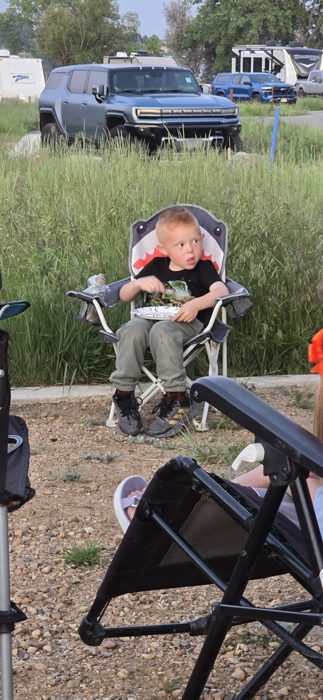 Kicking back in the camp chair amid the tall grass at the site, with the truck parked just behind.
