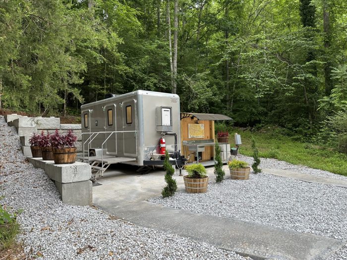 A tidy little campground bathhouse, framed by flower planters and tall pines at the Myrtle Beach KOA.