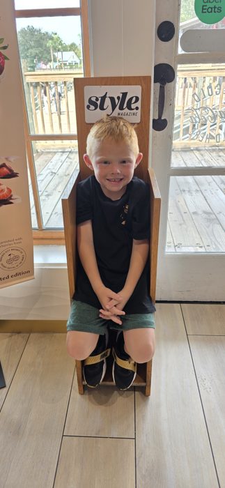 Another silly pose in the shop's wooden photo-op chair before exploring the boardwalk.
