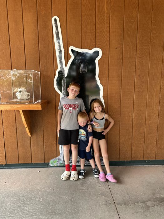 The kids pose with the giant black bear statue at Bear Country USA.