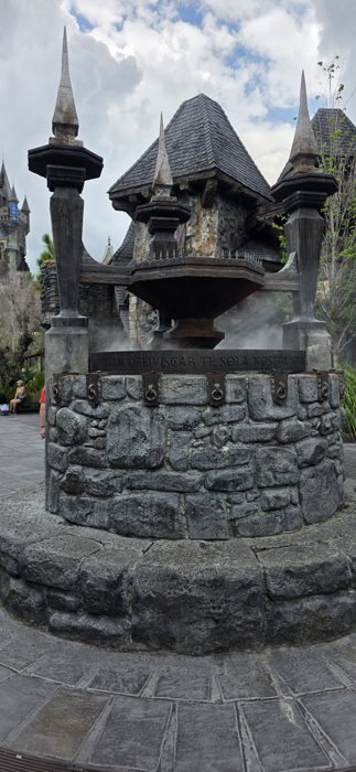 Another angle on the misty cauldron fountain, framed by the fairy-tale rooftops behind it.
