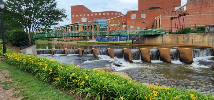 A riverside look at downtown Greenville's brick mills and footbridges along the Reedy.