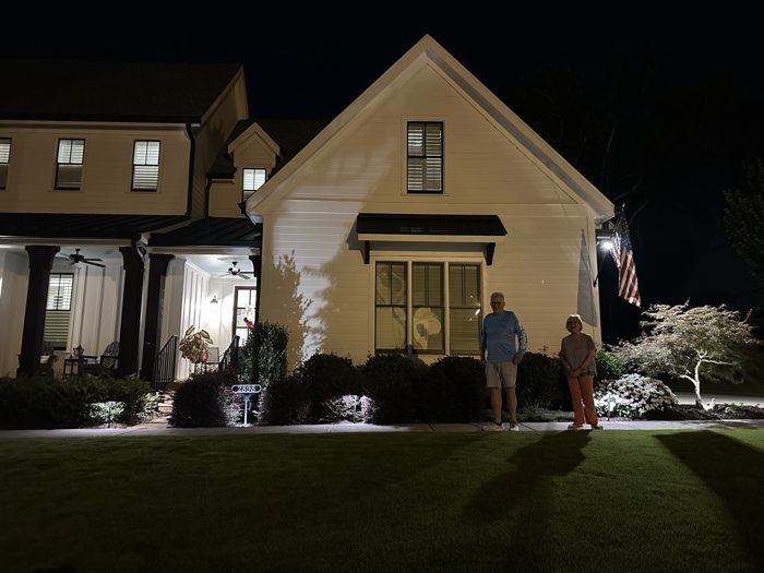 An evening goodbye with family, porch and yard lights glowing warm against the dark.