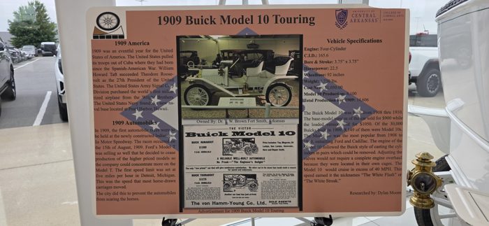 A placard tells the story of the vintage 1909 Buick Model 10 Touring parked at the dealership showroom.