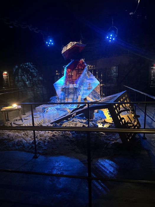 A coffin tips eerily in ghostly blue light inside the ride's crypt scene.