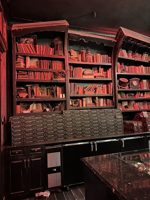 Rows of red-lit antique books line the shelves inside Gideon's Bakehouse's spooky-chic interior at Disney Springs.