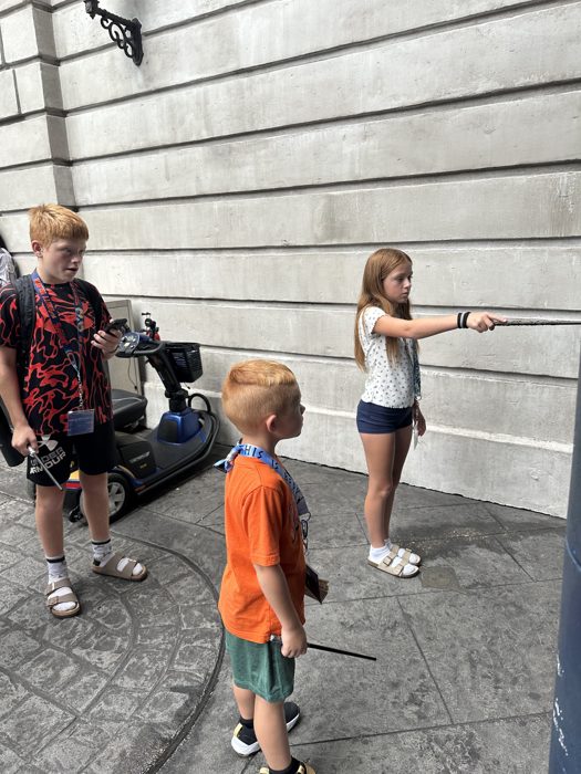 The kids take turns testing an interactive wand at one of Diagon Alley's shop windows.