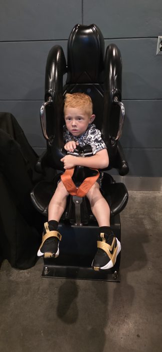 A more wide-eyed look this round, arms wrapped around the harness bar before the ride.