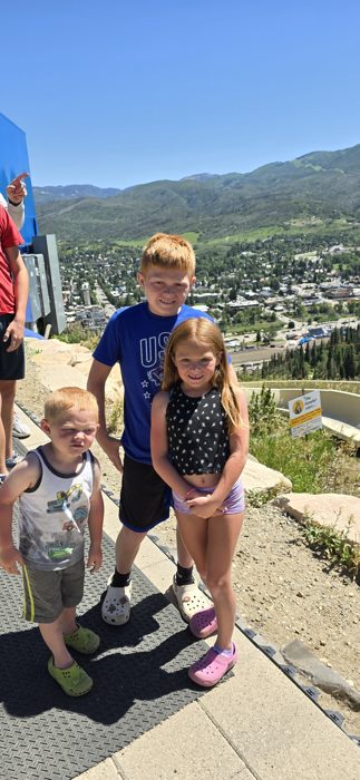 The three kids pose at the Howelsen Hill overlook with the whole Steamboat valley behind them.