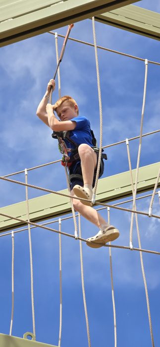 Reaching for the next handhold way up on the ropes course.