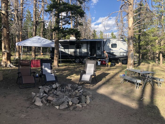 Home base all set up under the pines near Saratoga, with the canopy, camp chairs, and picnic table ready to go.