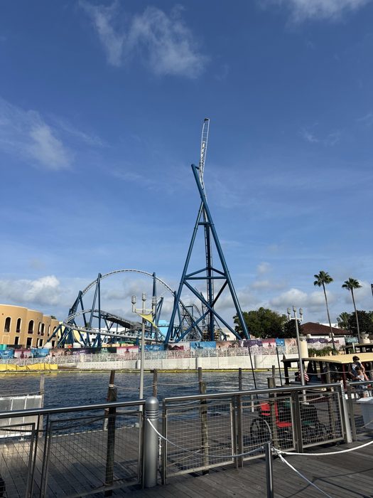 Coaster tracks and palm trees rise over the lagoon on a bright morning at Universal.