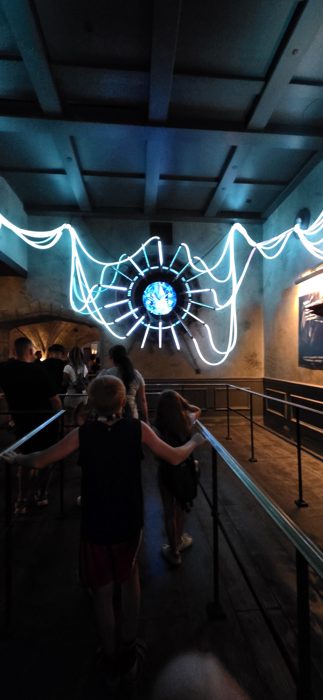 The kids leaning on the rail, taking in the glowing light display in the queue.