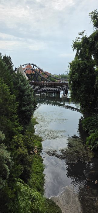A quiet lagoon view with a roller coaster looping through the park in the distance.