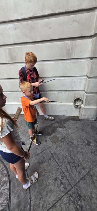The kids take turns testing their wands along a stone wall, hoping for a spark of magic.