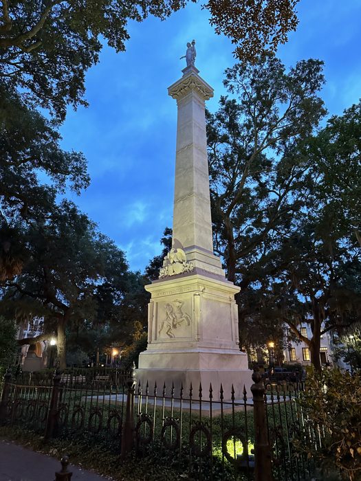 A towering monument set against the deep blue dusk in a Savannah square.