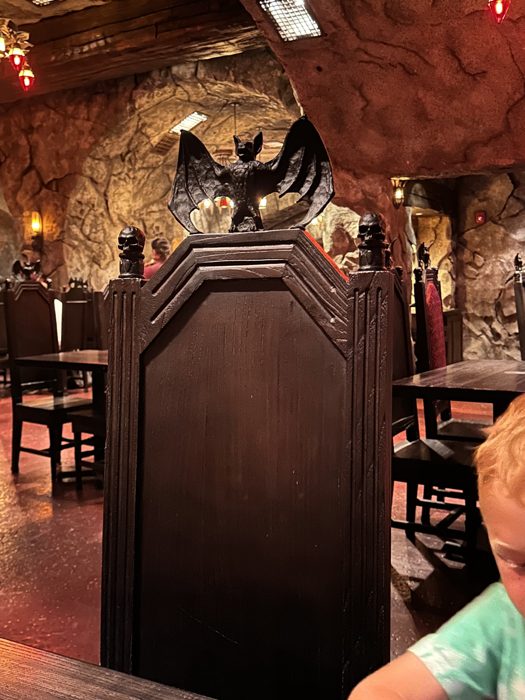 One of the kids peeking around a bat-topped coffin booth in the spooky dining room.