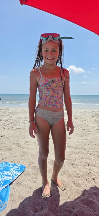 Sun-pinked cheeks and a dive mask pushed up on her head after a morning of snorkeling off the beach.