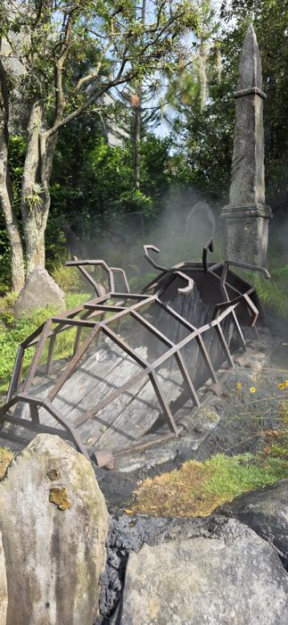 A wrecked mine cart sits half-buried among the tombstones and drifting fog.
