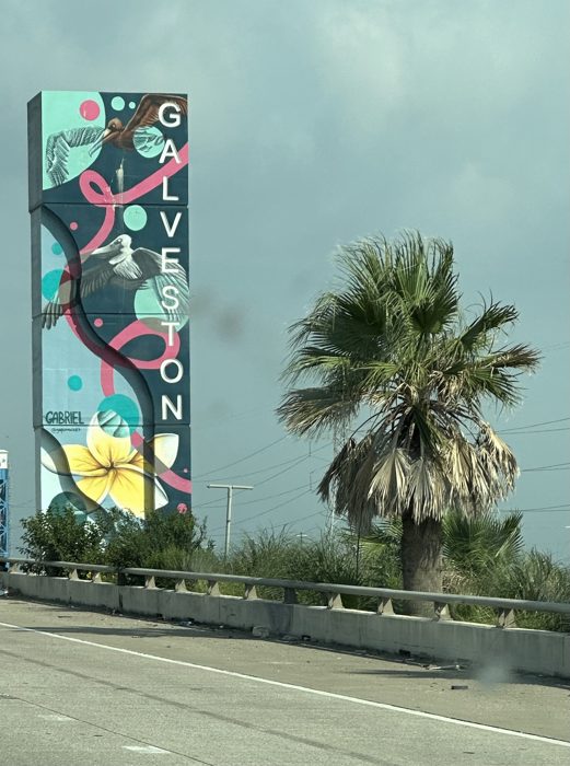 A vibrant mural tower and a lone palm catching the light along the roadside.