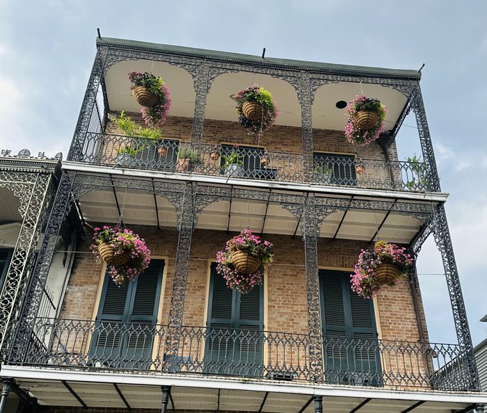 Wrought-iron galleries dripping with greenery on a French Quarter corner building.