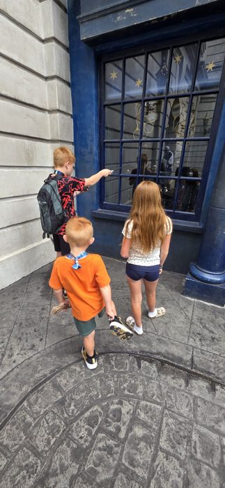 Wands raised at a shop window, waiting to see which one triggers the magic.