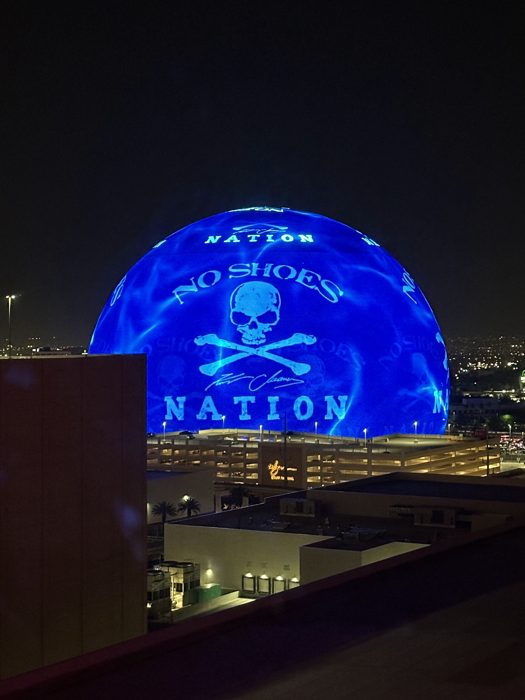 The Las Vegas Sphere glowing over the Strip at night.