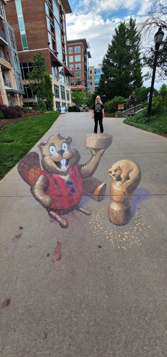 Marveling at a playful 3D sidewalk chalk squirrel along a downtown Greenville walking path.