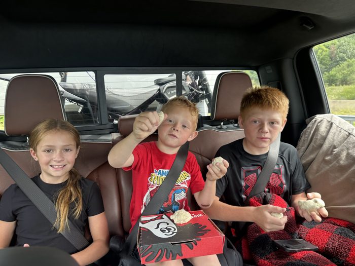 The kids goof around with balls of leftover pizza dough in the back seat.