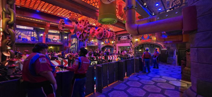 Weaving through the gear-and-pipe themed queue for the Mario Kart ride, crew in racing colors keeping the line moving.