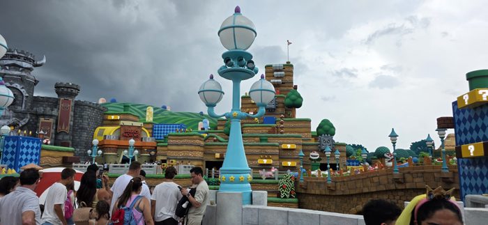 A giant star-topped lamp post rises over the crowd, with the colorful hills and pipes of the video-game-themed land spreading out behind it.