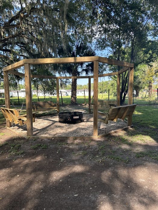 A cozy pergola fire-pit lounge with chairs overlooking the water at the RV park.