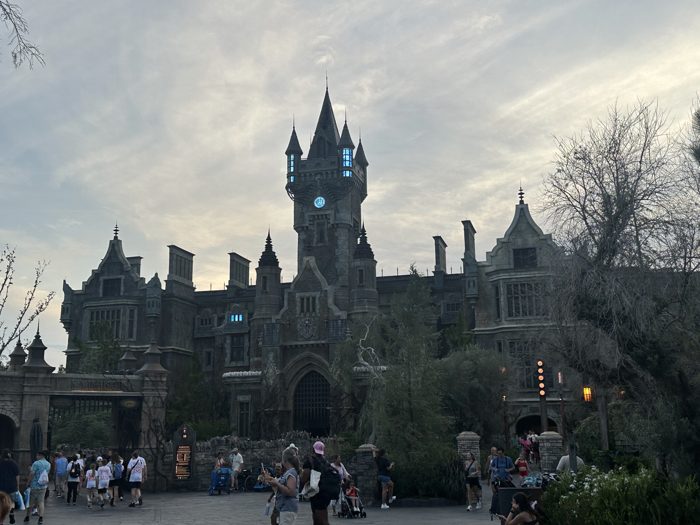 Families stream past the castle's gothic facade as the sky fades to dusk.