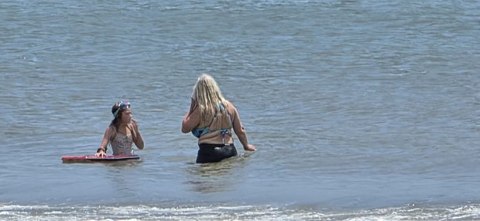 Chatting it out in the surf, boogie board floating between them.