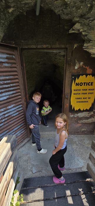 The kids strike a pose at the rugged stone entrance before heading down into the cave.